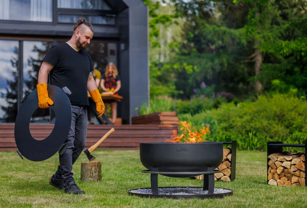 Man by a COOK KING fire bowl in the garden