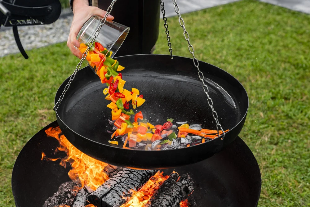 Vegetables poured onto a COOK KING griddle plate over the fire